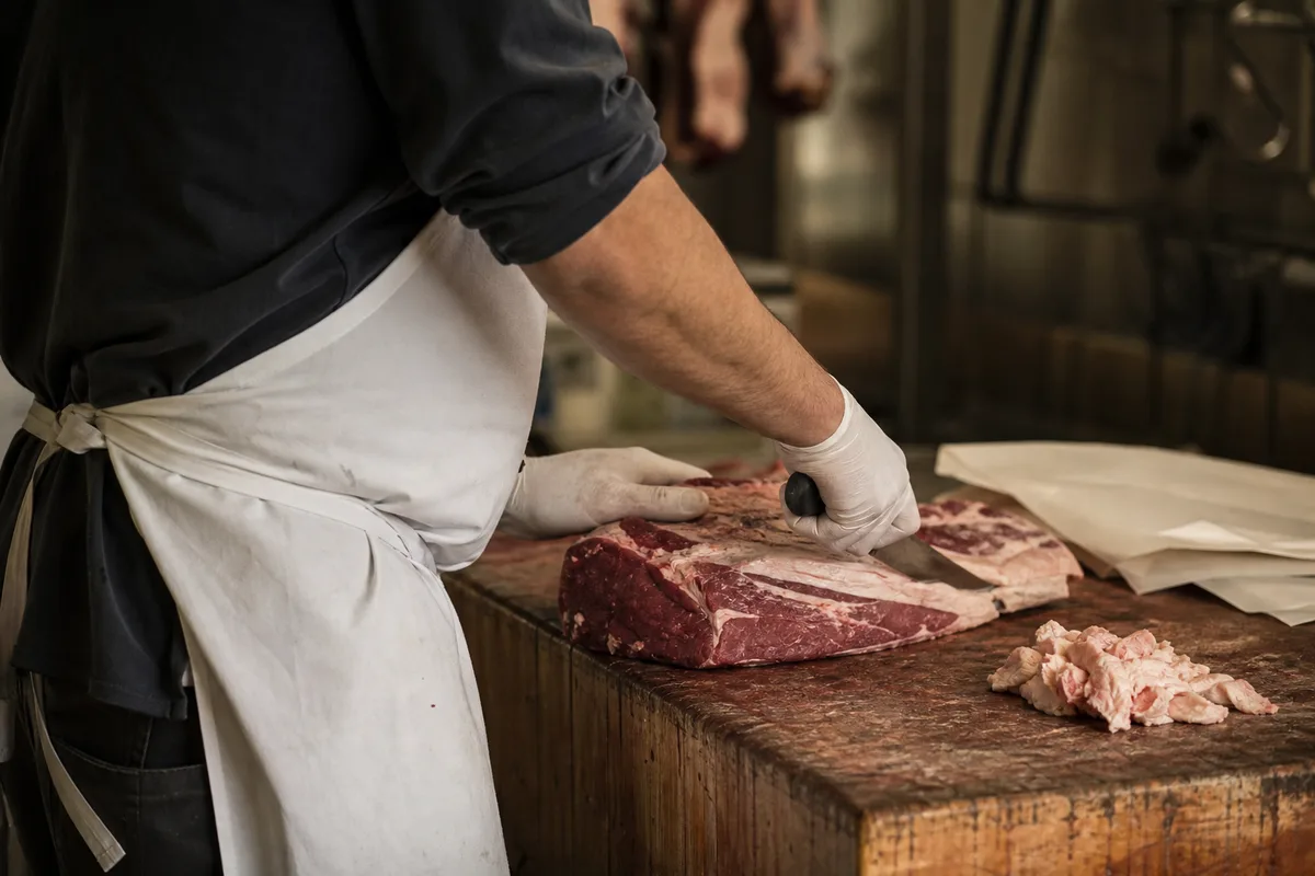 Boucher préparant une commande sur mesure sur un billot en bois