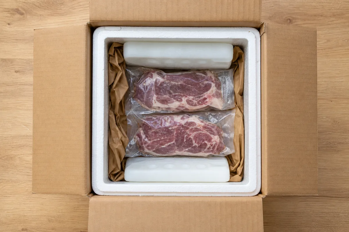 Colis isotherme ouvert avec pièces de viande sous vide et plaques de froid